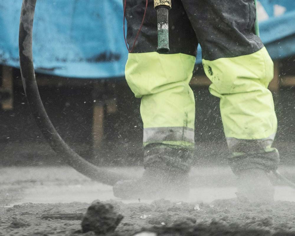 Construction worker using a jackhammer on pavement.