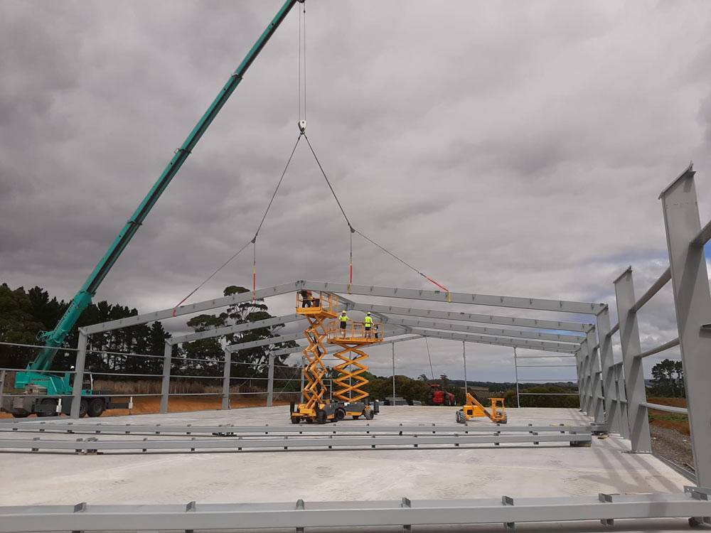 Construction workers assembling a steel structure with a crane.