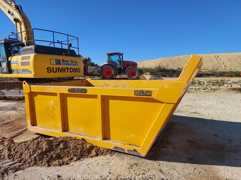 Yellow Sumitomo excavator bucket on a construction site.